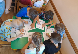 Na zdjęciu widać dzieci które wykonują zadania w kartach pracy.