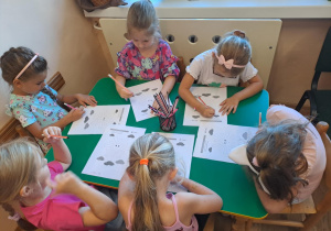 Na zdjęciu widać dzieci które wykonują zadania w kartach pracy.