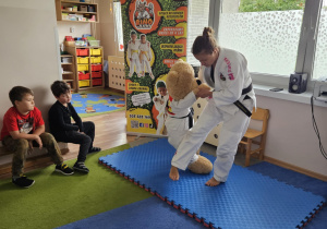 Na zdjęciu widać dzieci które obserwują zajęcia pokazowe Judo.