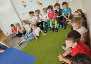 Na zdjęciu widać dzieci które obserwują zajęcia pokazowe Judo.