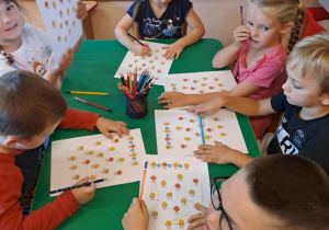 Na zdjęciu widać dzieci które wykonują kartę pracy z Okazji Dnia Kropki.
