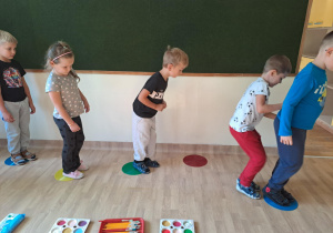 Na zdjęciu widać dzieci które wykonują podskoki na kropkach. Zabawy ruchowe.