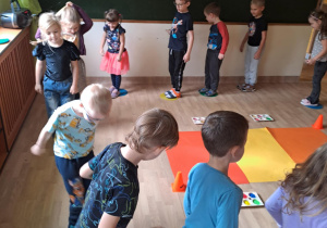 Na zdjęciu widać dzieci które wykonują podskoki na kropkach. Zabawy ruchowe.
