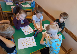 Na zdjęciu widać dzieci które wykonują kartę pracy z Okazji Dnia Kropki.