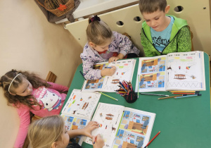 Na zdjęciu widać dzieci które pracują w książkach.