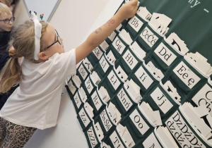 Na zdjęciu widać dziecko przy tablicy z literami.