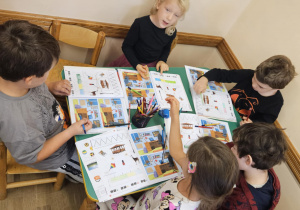 Na zdjęciu widać dzieci które pracują w książkach.