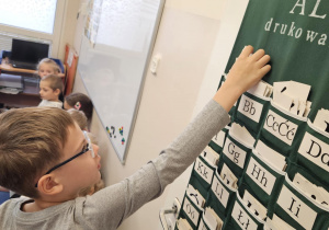 Na zdjęciu widać dziecko przy tablicy z literami.