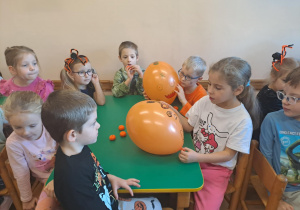 Na zdjęciu widać dzieci przy stoliku dzieci z balonami.