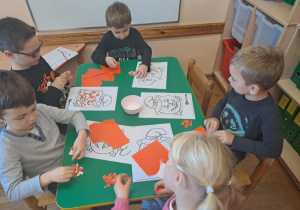 Na zdjęciu widać dzieci przy stoliku dzieci które robią prace plastyczną.