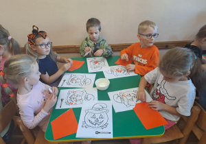 Na zdjęciu widać dzieci przy stoliku dzieci które robią prace plastyczną.