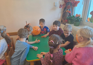 Na zdjęciu widać dzieci przy stoliku dzieci które robią prace plastyczną.