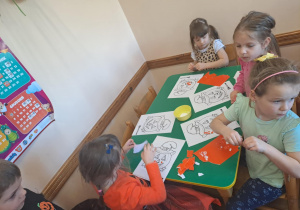 Na zdjęciu widać dzieci przy stoliku dzieci które robią prace plastyczną.