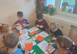 Na zdjęciu widać dzieci przy stoliku dzieci które robią prace plastyczną.