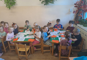 Na zdjęciu widać dzieci przy stoliku dzieci które robią prace plastyczną.