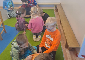 Na zdjęciu widać dzieci przy stoliku dzieci które robią prace plastyczną.