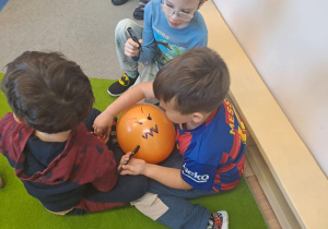 Na zdjęciu widać dzieci przy stoliku dzieci które robią prace plastyczną.