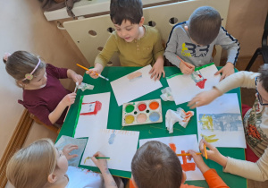 Na zdjęciu widać dzieci jak rysują kreatywną pracę plastyczną.