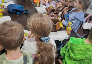 Na zdjęciu widać dzieci na warsztatach z dietetykiem. Dzieci jedzą kanapki.