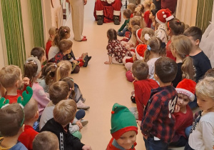 Na zdjęciu widać dzieci i Św Mikołaja który wręcza prezenty.