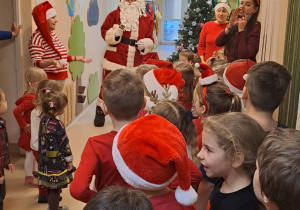 Na zdjęciu widać dzieci i Św Mikołaja który wręcza prezenty.