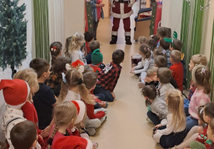 Na zdjęciu widać dzieci i Św Mikołaja który wręcza prezenty.