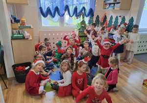 Na zdjęciu widać dzieci i Św Mikołaja który wręcza prezenty.