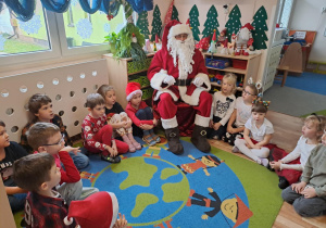 Na zdjęciu widać dzieci i Św Mikołaja który wręcza prezenty.