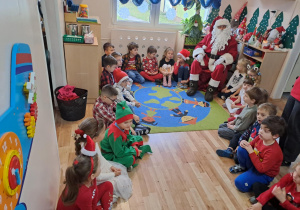 Na zdjęciu widać dzieci i Św Mikołaja który wręcza prezenty.