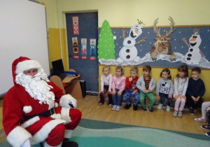 Na zdjęciu widać dzieci i Św Mikołaja który wręcza prezenty.