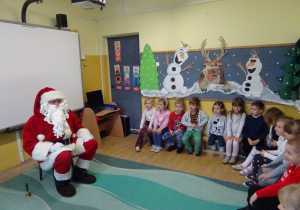 Na zdjęciu widać dzieci i Św Mikołaja który wręcza prezenty.