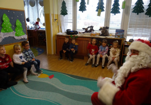 Na zdjęciu widać dzieci i Św Mikołaja który wręcza prezenty.