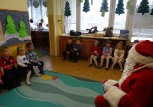 Na zdjęciu widać dzieci i Św Mikołaja który wręcza prezenty.