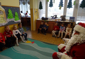 Na zdjęciu widać dzieci i Św Mikołaja który wręcza prezenty.
