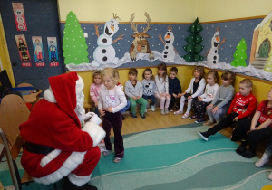 Na zdjęciu widać dzieci i Św Mikołaja który wręcza prezenty.