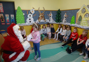 Na zdjęciu widać dzieci i Św Mikołaja który wręcza prezenty.