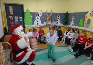 Na zdjęciu widać dzieci i Św Mikołaja który wręcza prezenty.