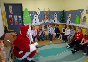 Na zdjęciu widać dzieci i Św Mikołaja który wręcza prezenty.