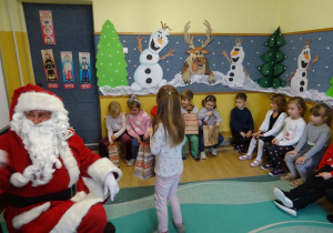 Na zdjęciu widać dzieci i Św Mikołaja który wręcza prezenty.