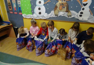 Na zdjęciu widać dzieci i Św Mikołaja który wręcza prezenty.