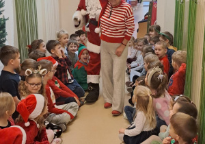 Na zdjęciu widać dzieci i Św Mikołaja który wręcza prezenty.