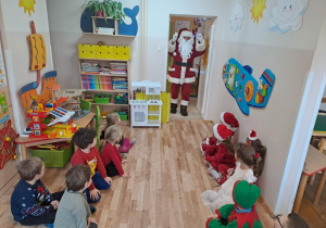 Na zdjęciu widać dzieci i Św Mikołaja który wręcza prezenty.