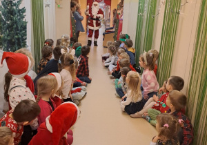 Na zdjęciu widać dzieci i Św Mikołaja który wręcza prezenty.