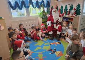Na zdjęciu widać dzieci i Św Mikołaja który wręcza prezenty.