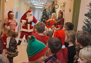 Na zdjęciu widać dzieci i Św Mikołaja który wręcza prezenty.