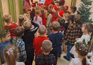 Na zdjęciu widać dzieci i Św Mikołaja który wręcza prezenty.