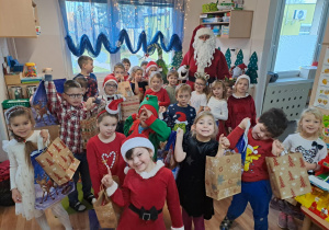 Na zdjęciu widać dzieci i Św Mikołaja który wręcza prezenty.