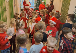 Na zdjęciu widać dzieci i Św Mikołaja który wręcza prezenty.