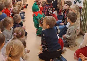 Na zdjęciu widać dzieci i Św Mikołaja który wręcza prezenty.