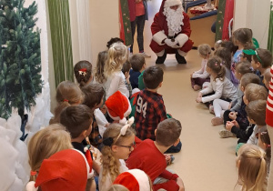 Na zdjęciu widać dzieci i Św Mikołaja który wręcza prezenty.